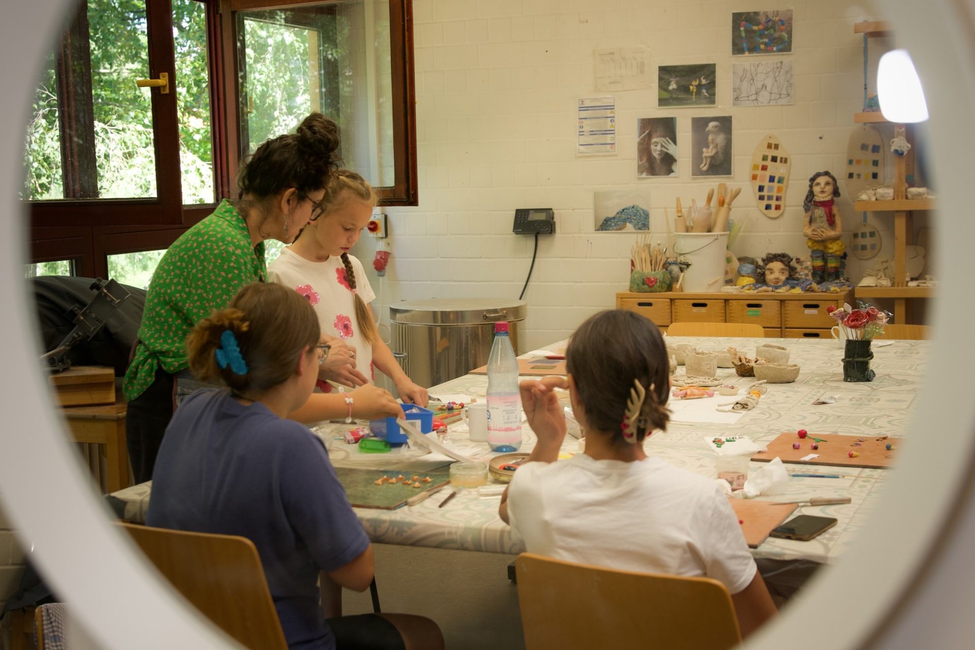 Family members craft together at a table in a creative studio, surrounded by artwork.