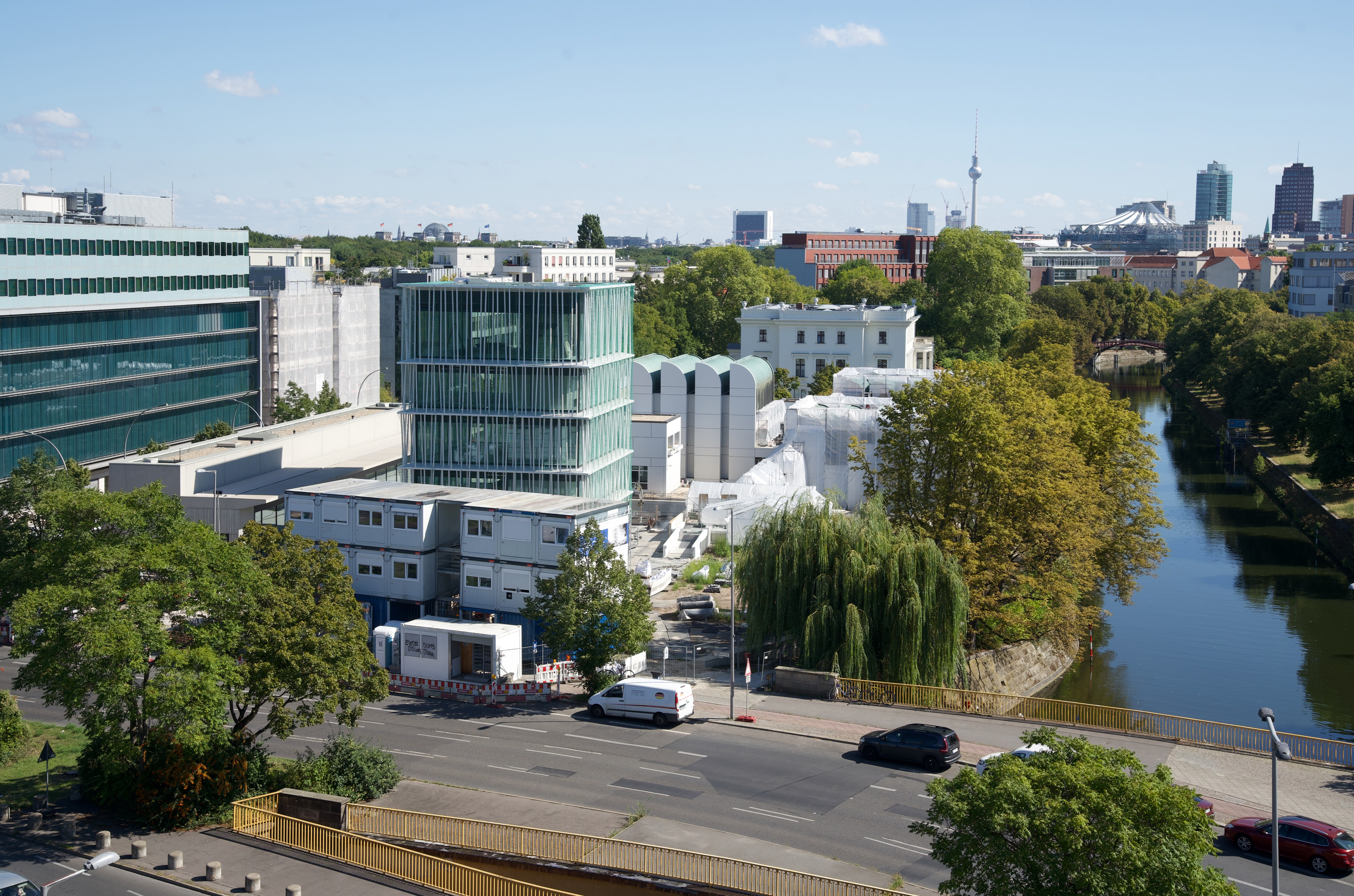 Städtische Landschaft mit modernen Gebäuden, Bäumen und einem Kanal an einem sonnigen Tag in Berlin.