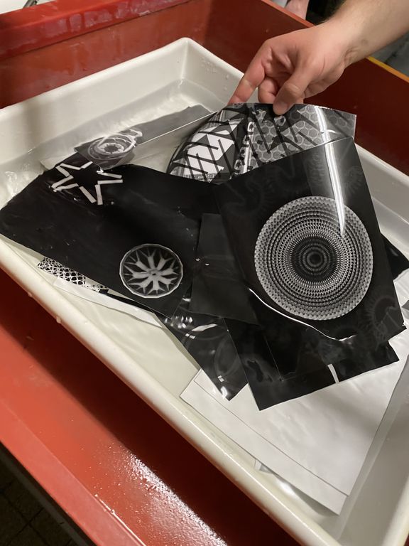 A hand holds printed black-and-white sheets in a water basin for processing.